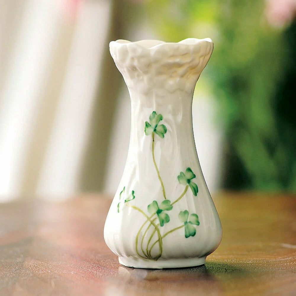 White vase with green shamrock design on a wooden surface