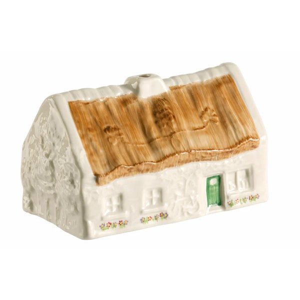 Ceramic model of a cottage with a thatched roof on a white background