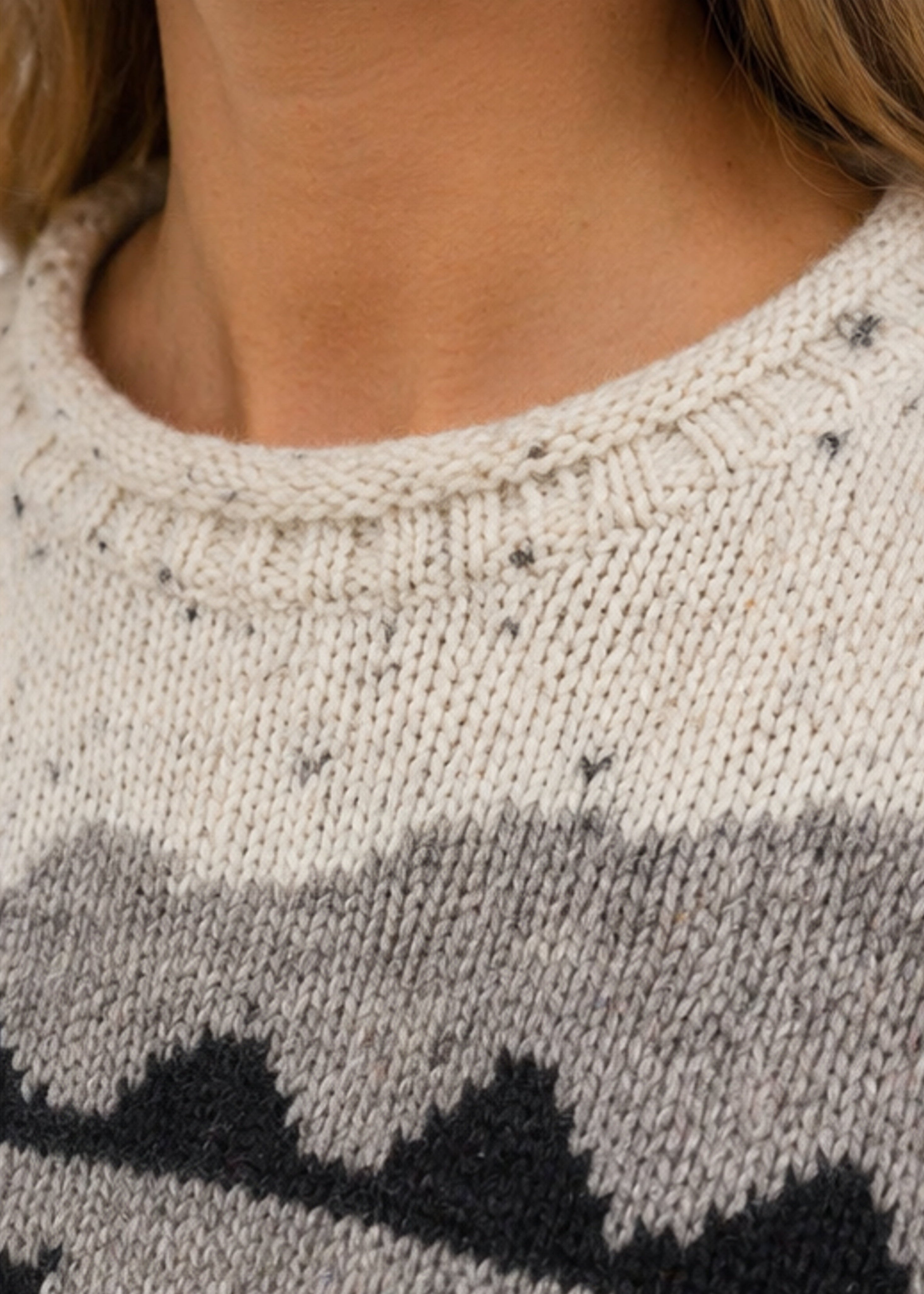 Close-up of a person wearing a knitted sweater with a patterned design.