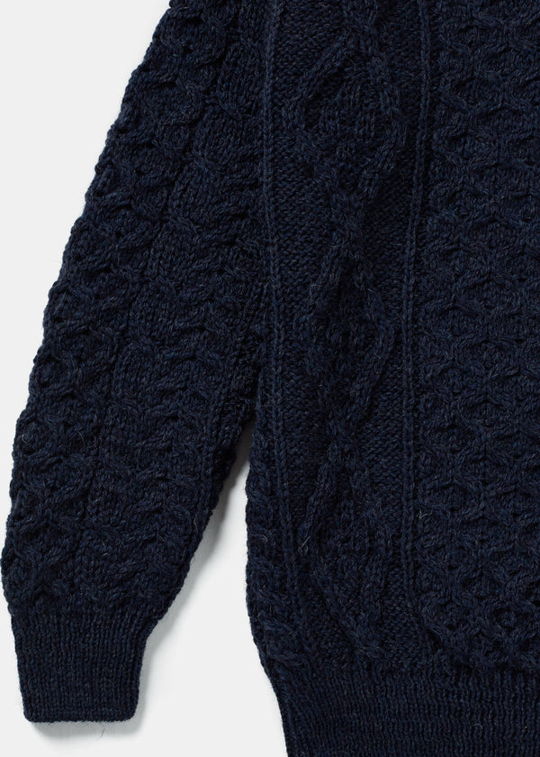 Close-up of a navy blue cable knit sweater on a white background