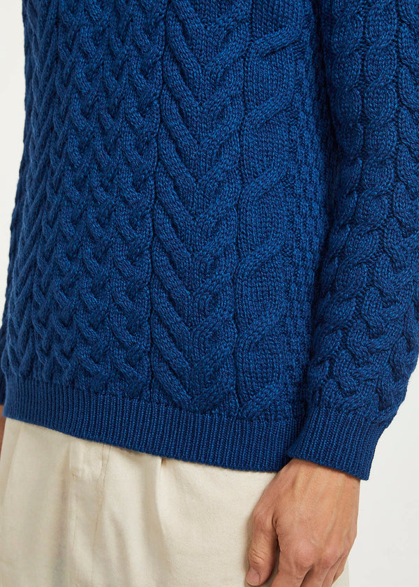 Close-up of a blue cable knit sweater on a plain background