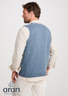 Man wearing a blue knitted vest over a white shirt on a white background, with 'Aran Woollen Mills' branding.