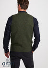 Man wearing a green knitted vest over a dark shirt on a white background