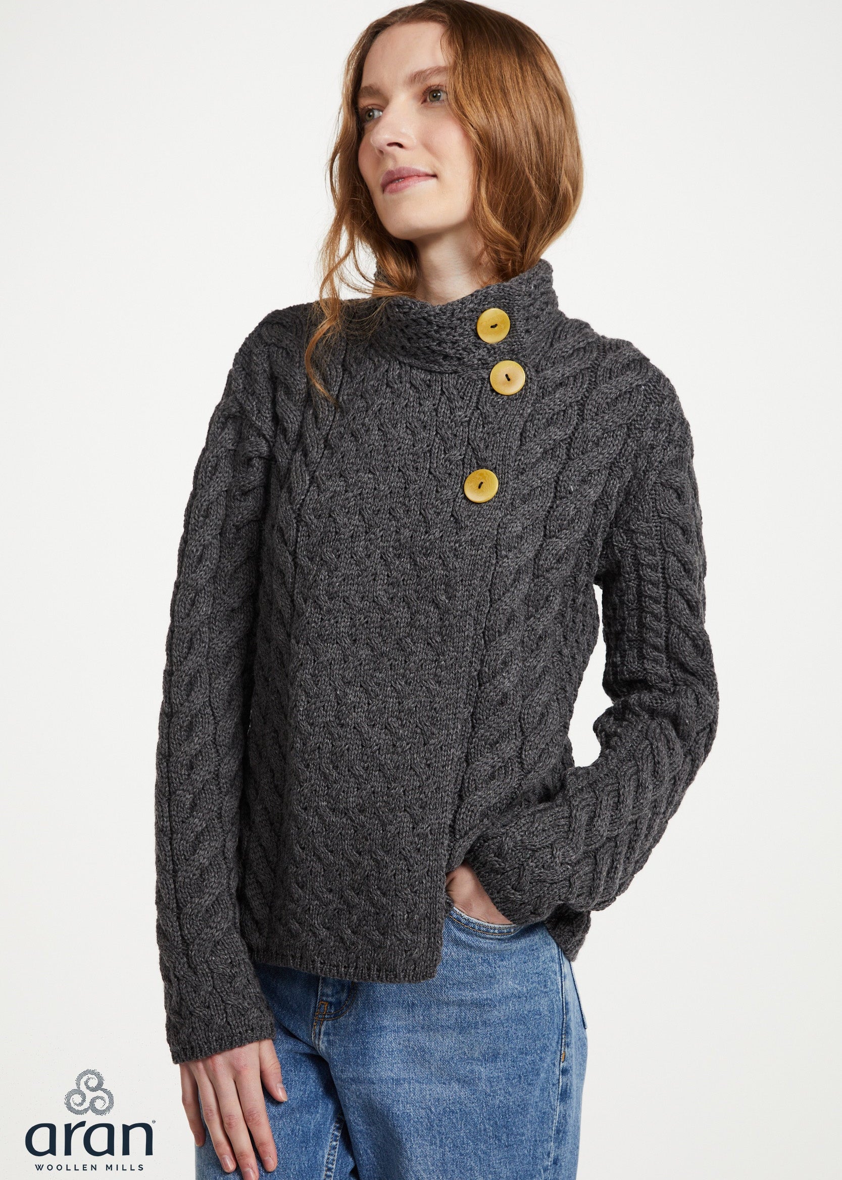 Woman wearing a dark gray cable knit sweater with yellow buttons on a white background