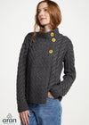 Woman wearing a dark gray cable knit sweater with yellow buttons on a white background