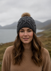 Woman wearing a gray knit beanie with a pom-pom in a mountainous landscape