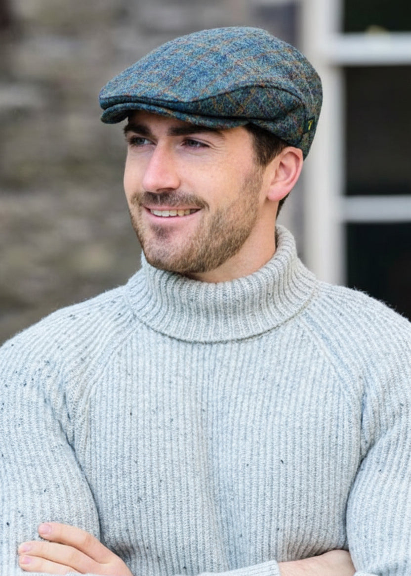 Man wearing a textured cap and light sweater outdoors.