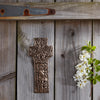 Bronze cross on a wooden surface with white flowers and green leaves