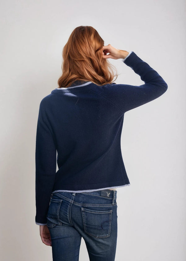 Person wearing a navy sweater and blue jeans against a plain background