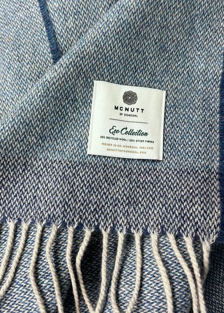 Close-up of a blue and white woven scarf with cream fringe and a visible McNutt of Toronto label.
