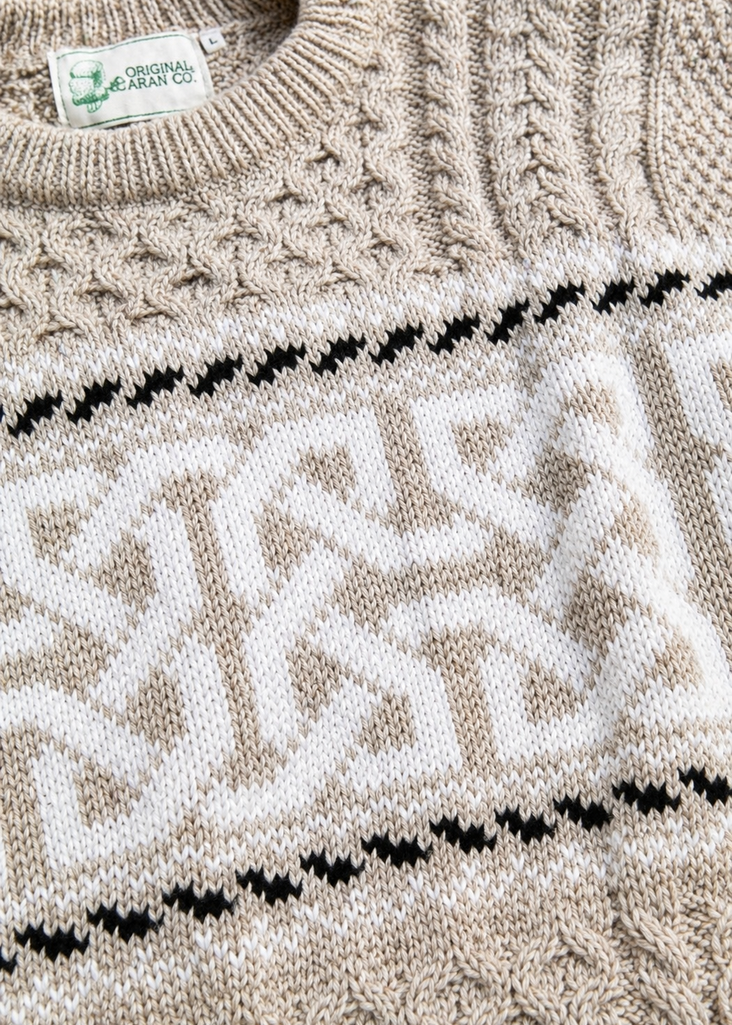Close-up of a knitted sweater with a pattern and 'Original Design Co' label.