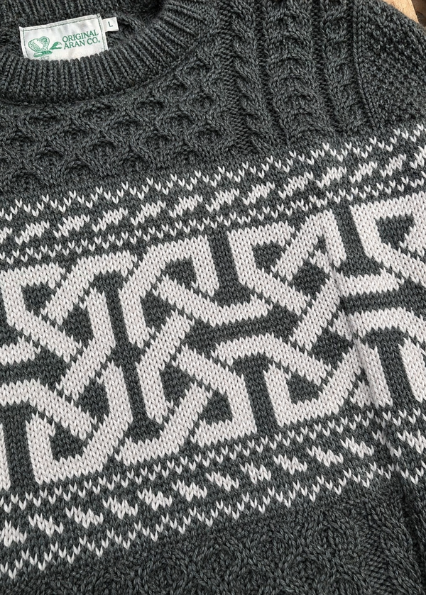 Close-up of a dark gray sweater with a geometric pattern, featuring a brand label.