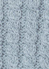 A close-up of a light blue-gray cable-knit fabric texture, showing the detailed knit pattern and soft yarn fibers.