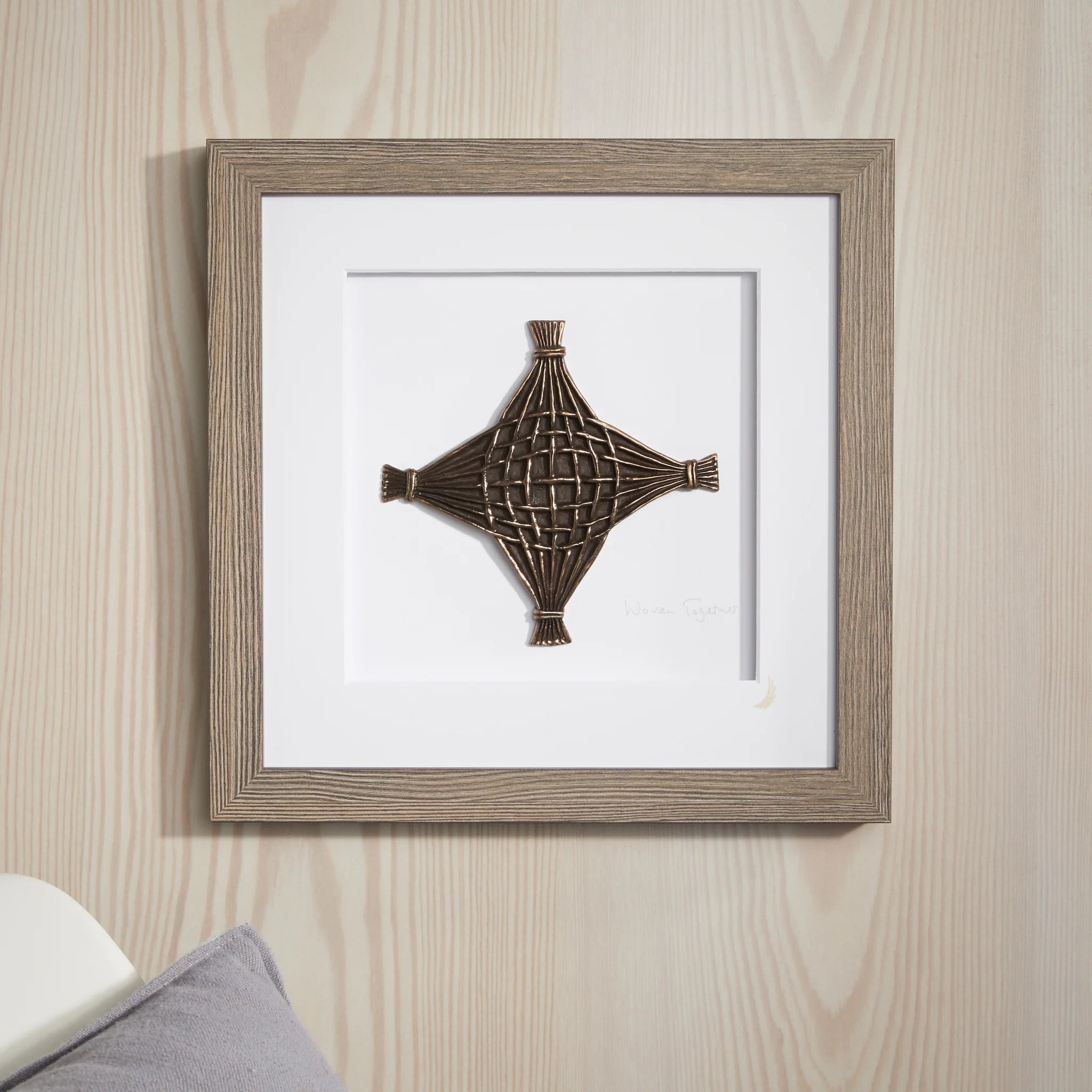 Framed decorative wall art with a geometric design on a wooden wall.