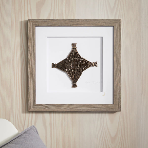 Framed decorative wall art with a geometric design on a wooden wall.