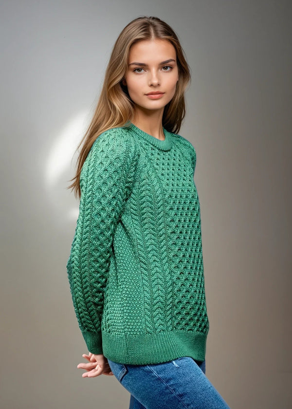 Woman wearing a green knitted aran sweater against a gray background