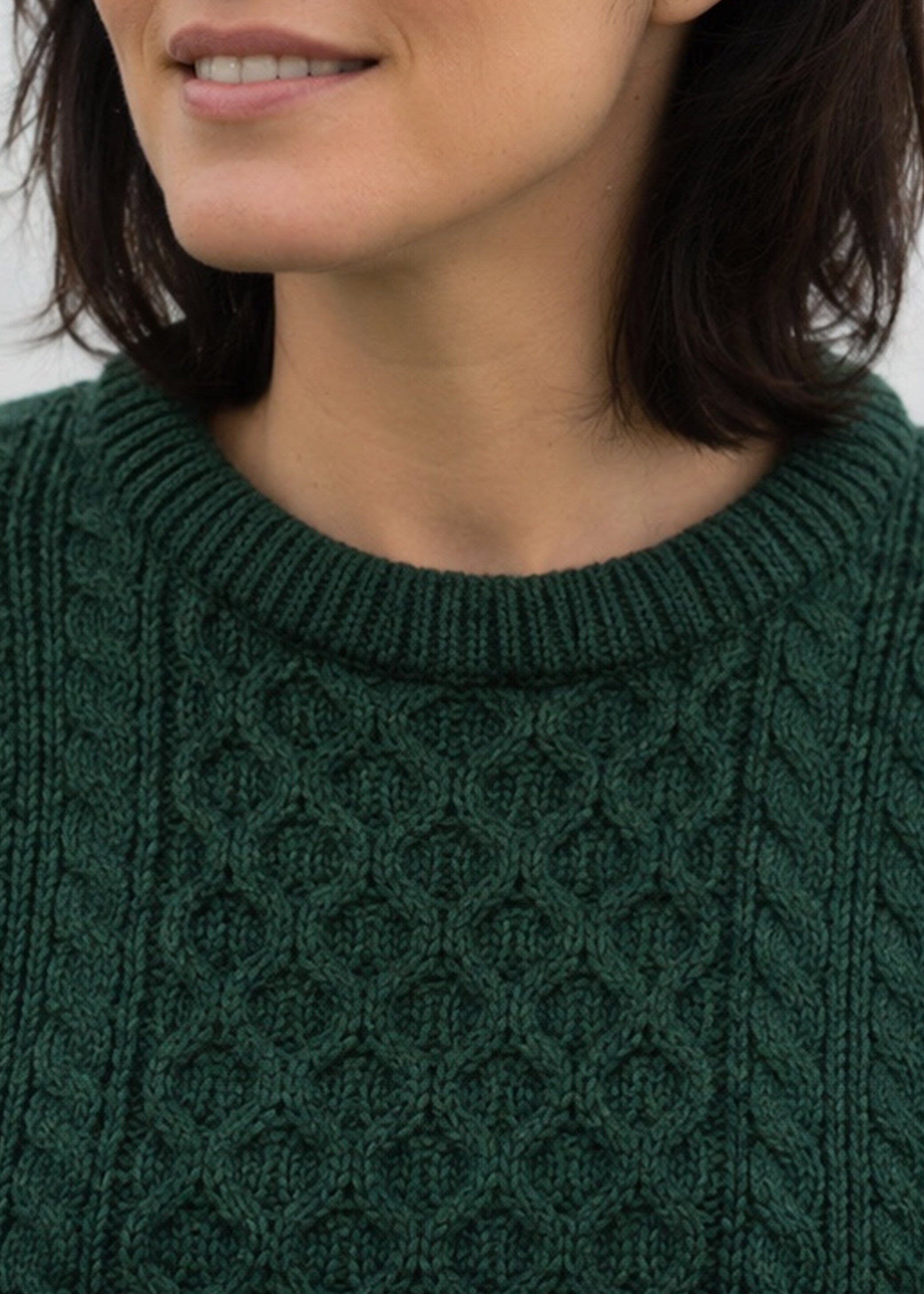 Close-up of a person wearing a green cable knit sweater