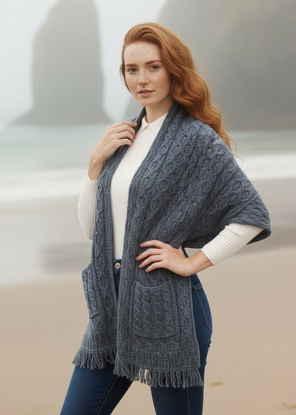 Woman wearing a blue knitted poncho against a neutral background