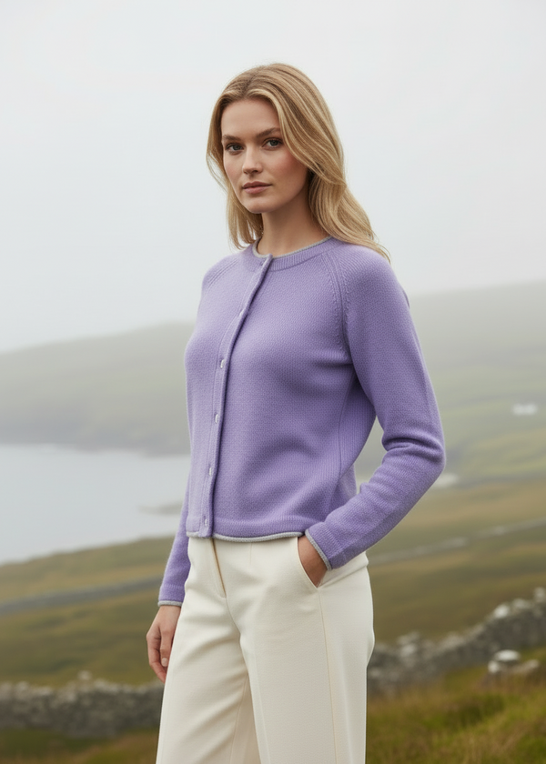Woman wearing a purple cardigan standing in a scenic outdoor setting.