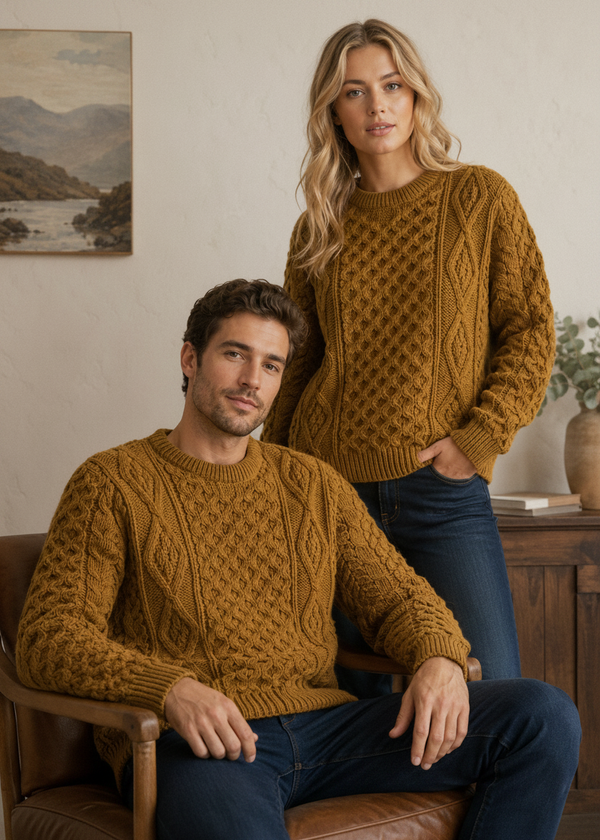 Man and woman wearing matching mustard yellow cable knit sweaters in a cozy room.