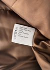 Clothing label on a brown fabric surface with material information.