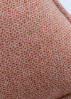 Close-up of a textured red-brown fabric with a subtle pattern on a white background