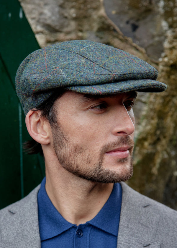 Man wearing a patterned cap and gray coat outdoors
