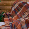 Plaid blanket draped over a chair with a wooden background