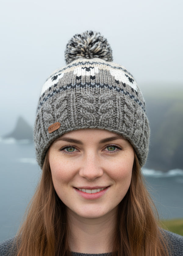 Knitted beanie with a sheep pattern and pom-pom on a white background