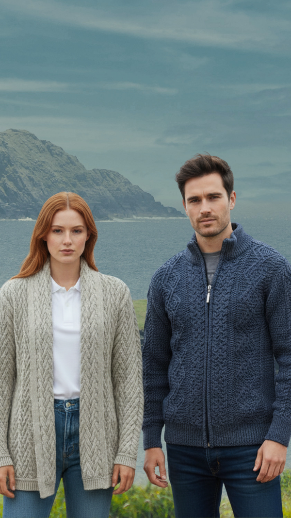 Two people wearing knitted cardigans standing outdoors with a mountainous background