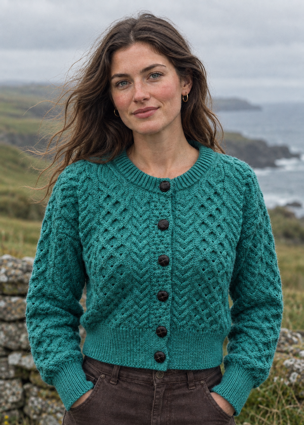 Model in the teal Aran cardigan by a stone wall on an Irish headland