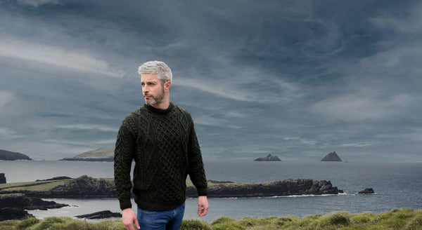 Man standing on a coastal landscape with islands and a dark sky.