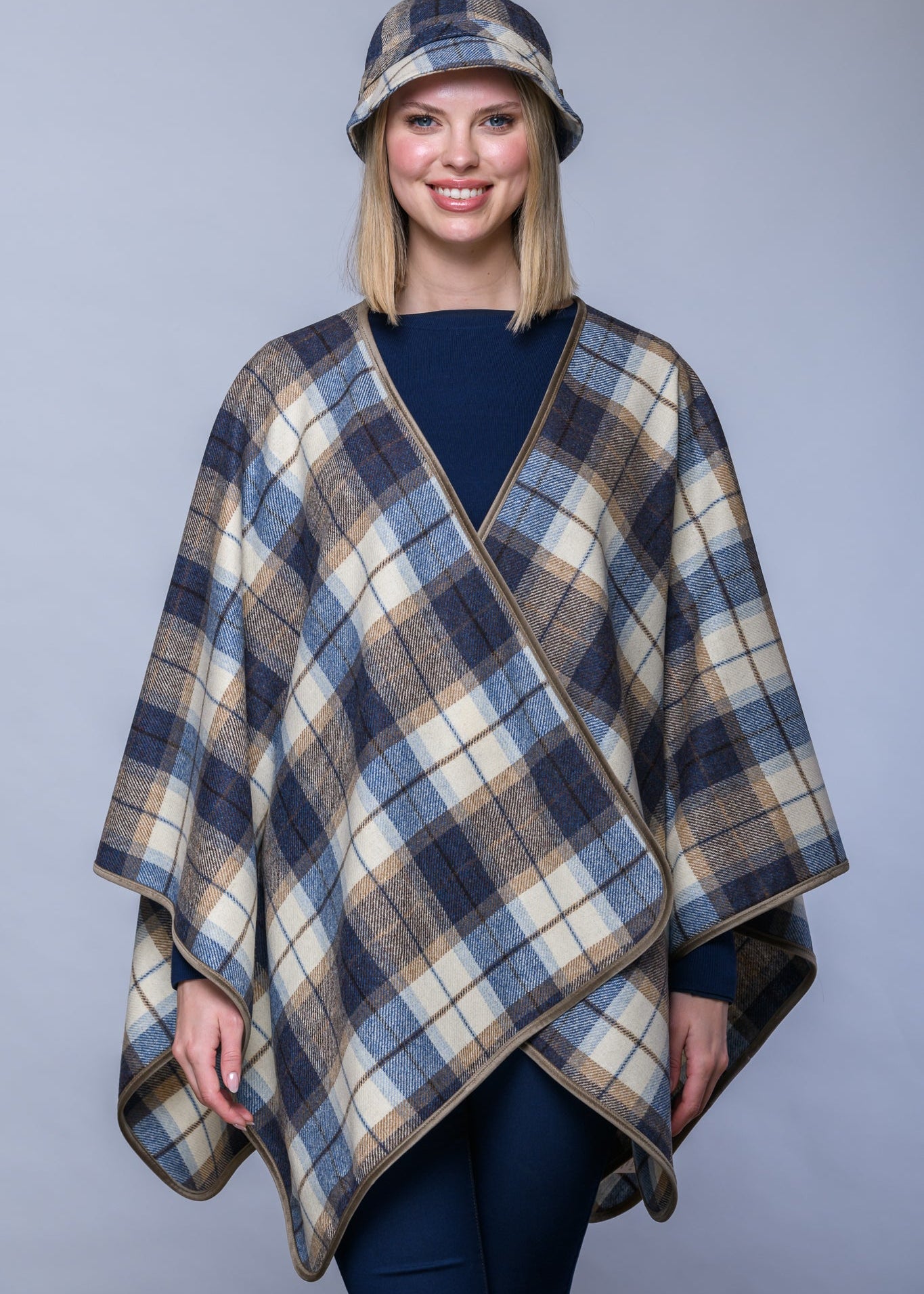 Person wearing a plaid poncho against a plain background