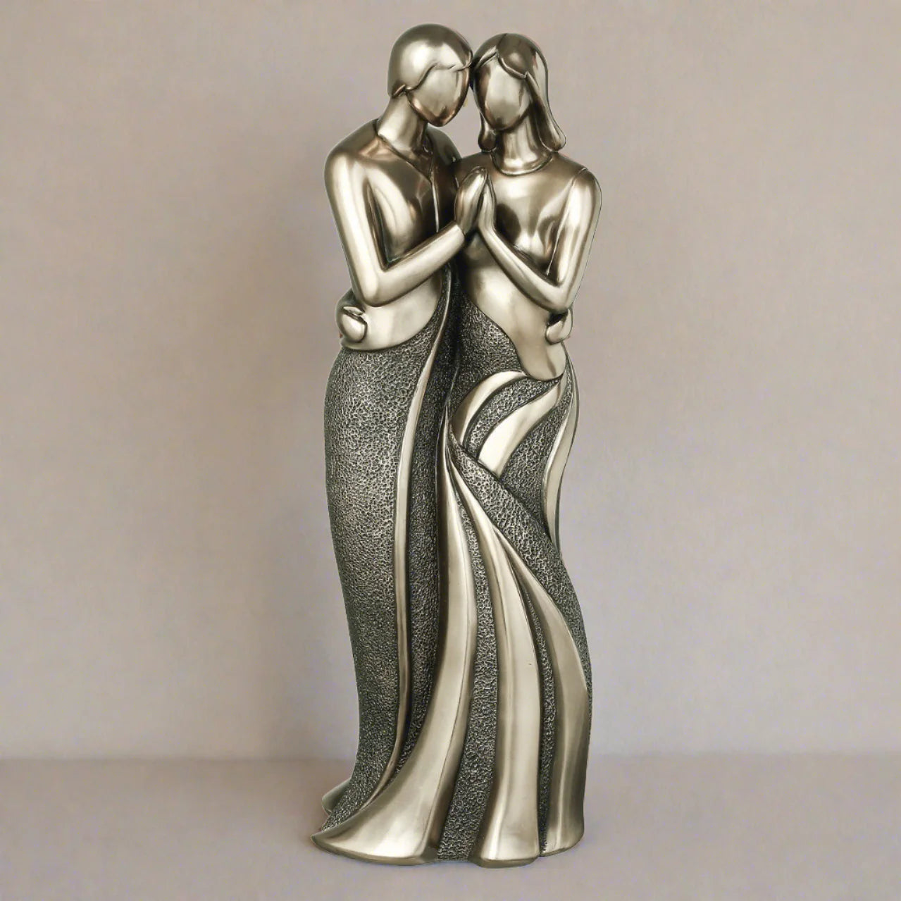 Statue of two people embracing on a plain background