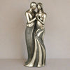 Statue of two people embracing on a plain background