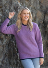 Woman wearing a purple sweater standing against a stone wall