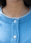 Close-up of a blue cardigan with white buttons on a dark background