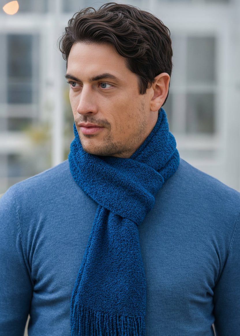Man wearing a blue scarf and sweater with a blurred background