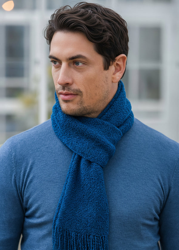 Man wearing a blue scarf and sweater with a blurred background