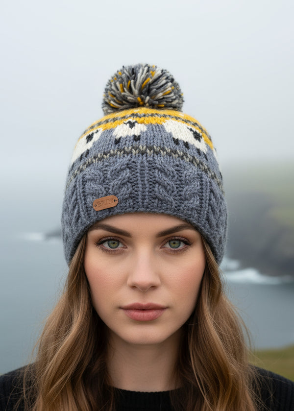 Woman wearing a gray knit sheep beanie with a pom-pom in a misty outdoor setting