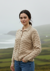 Woman wearing a beige knitted cardigan with a scenic background