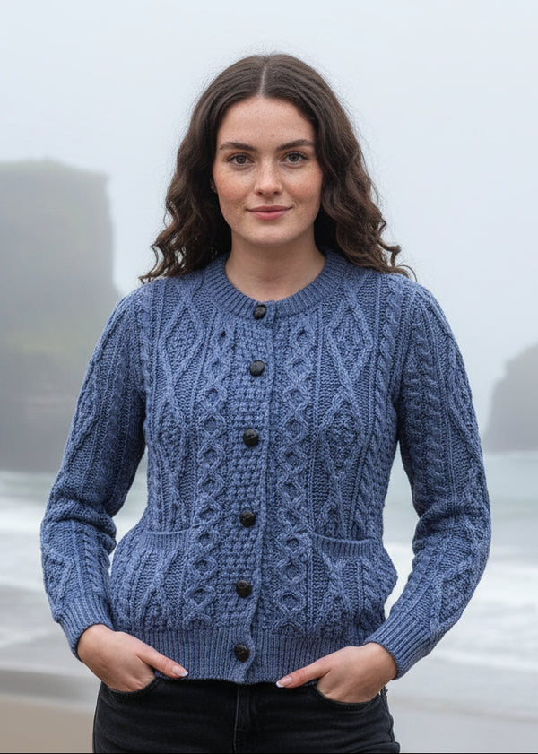 Woman wearing a blue knitted aran cardigan standing by the ocean