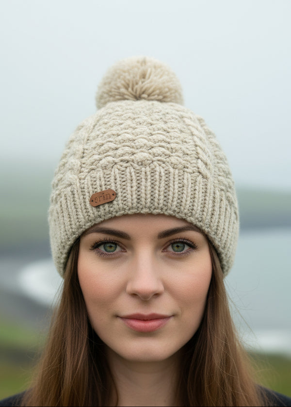 Knitted erin oatmeal beanie with pom-pom on a white background