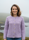 Lifestyle image of female model wearing soft lavender Aran cardigan