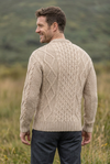 Oatmeal Aran sweater, smiling over-the-shoulder back pose in the matching grassland setting