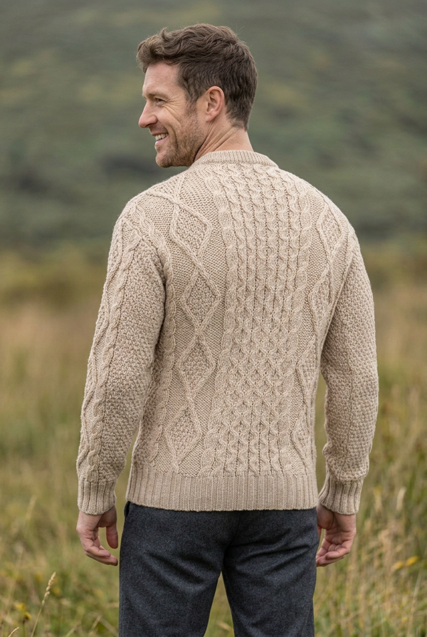 Oatmeal Aran sweater, smiling over-the-shoulder back pose in the matching grassland setting