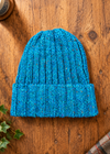 100% Donegal wool turn-up beanie hat in blue on a rustic wooden table